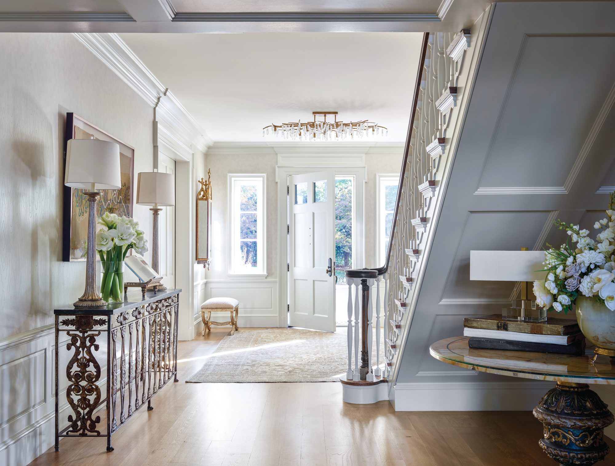 Foyer with a retained staircase and scrolled iron railing, an antique console, and circa 1820 Italian church panels turned into sconces
