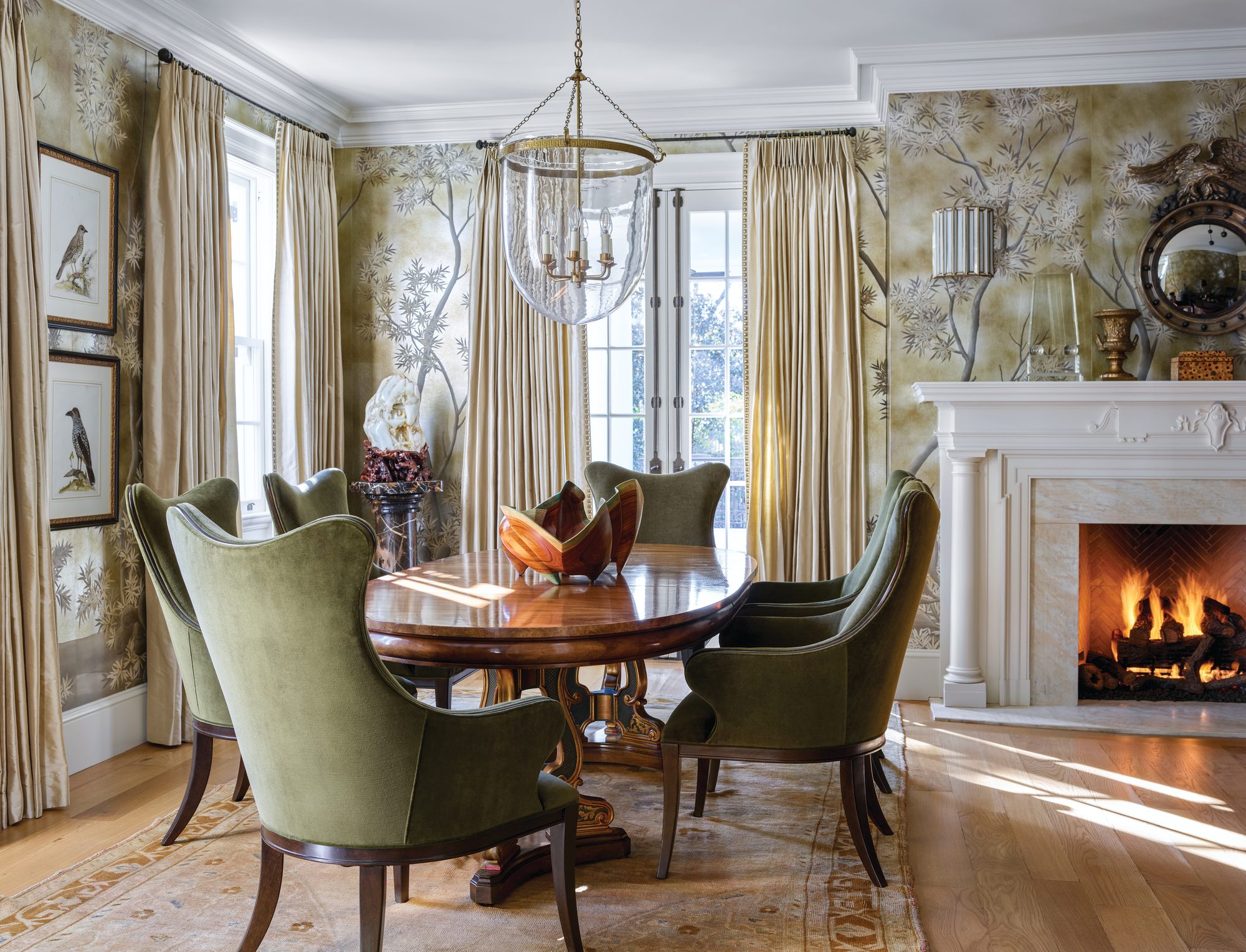 Front office with green chinoiserie wallpaper, a marble mantel, and an oval mahogany conference table ringed with green velvet chairs