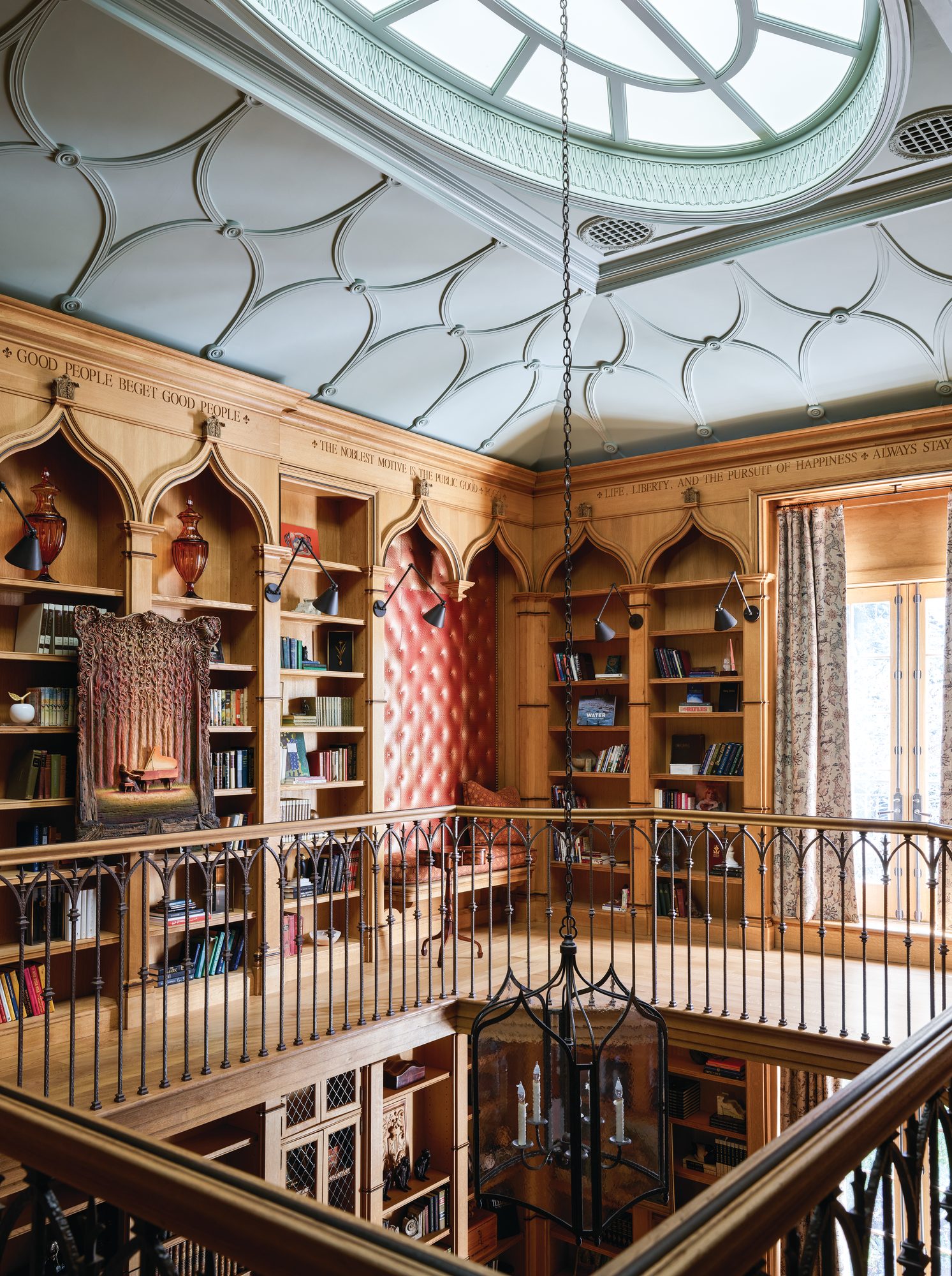 Two-level wood-paneled library seen from the balcony, with etched quotes along the top and ornamentation surrounding the skylight
