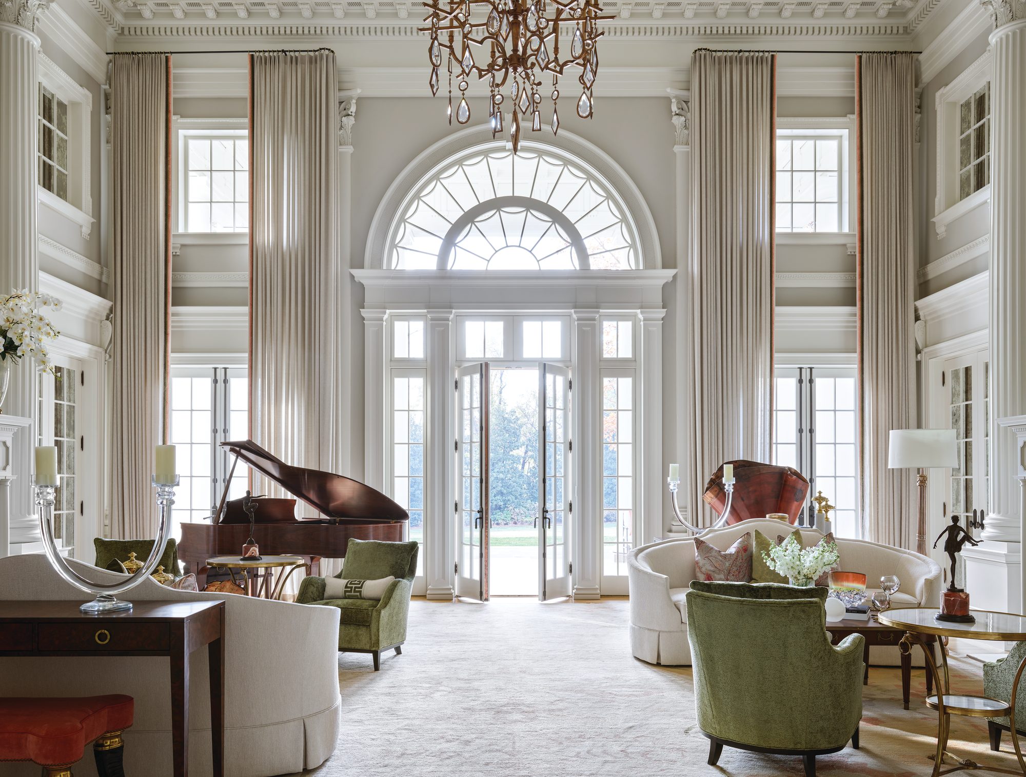 Two-story grand salon with white walls, fluted columns, an arched fanlight door, a grand piano, and a gilded ceiling dome