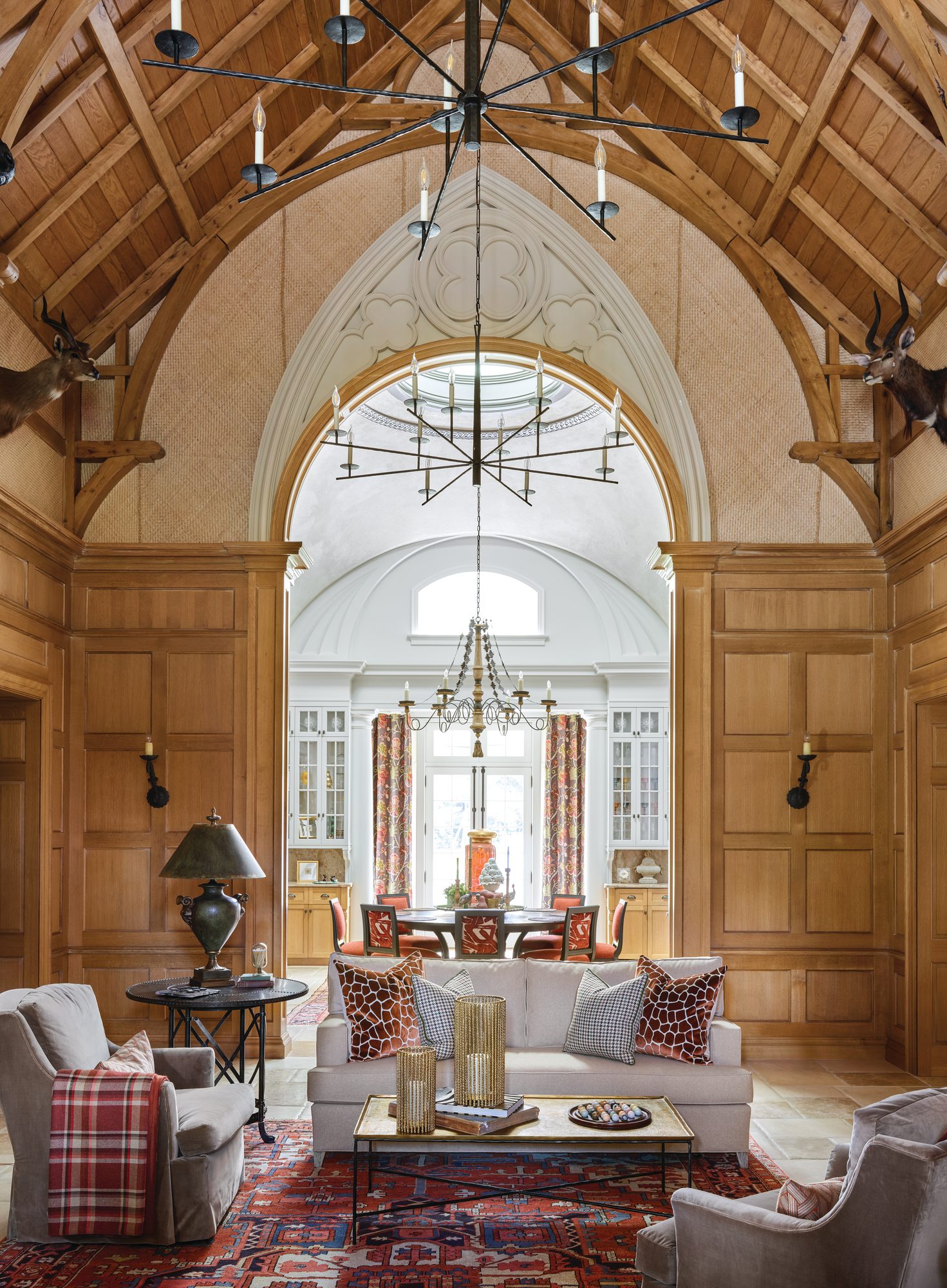 Den with rich wood paneling, a timbered ceiling, and an ornate archway framing the opening into the breakfast room