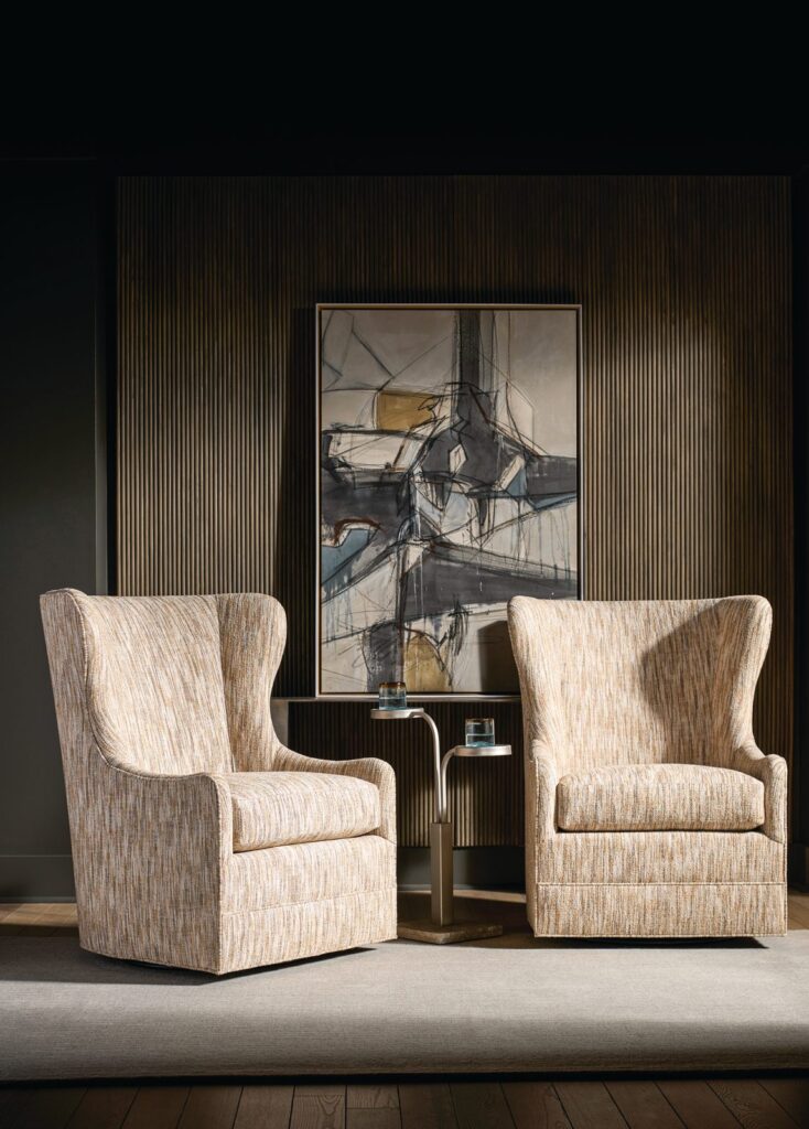 Pair of Amarillo swivel wing chairs in a textured neutral fabric beneath an abstract painting