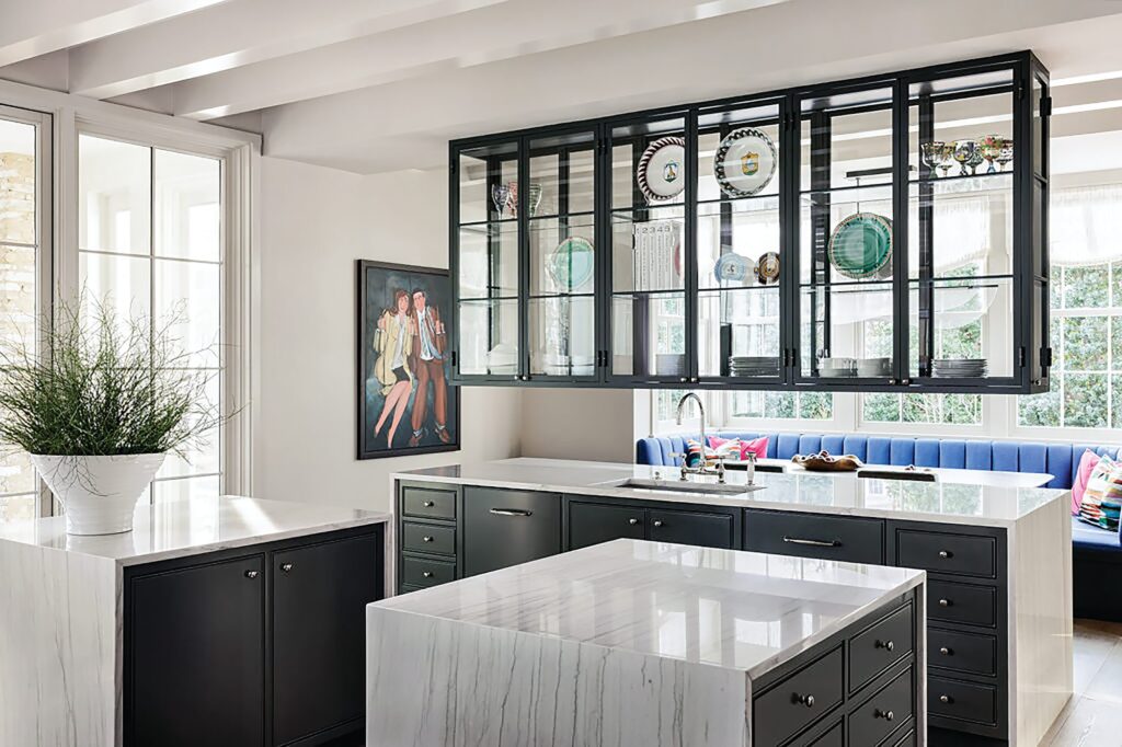 Kitchen with suspended black steel and glass cabinetry displaying dishware above a marble waterfall island with dark cabinets