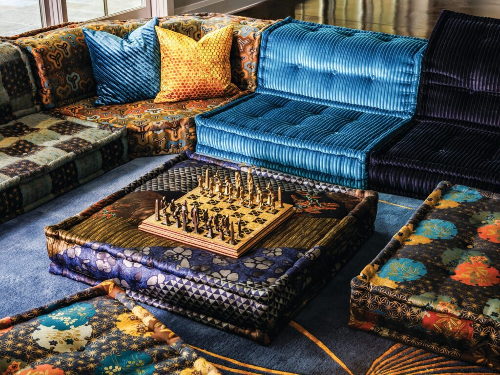 Recreation room with a Roche Bobois Mah Jong sofa covered in colorful Kenzo fabrics and a chess set on a low upholstered table