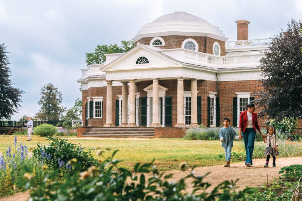Family walking past garden beds in front of Thomas Jefferson’s domed Monticello in Charlottesville, Virginia