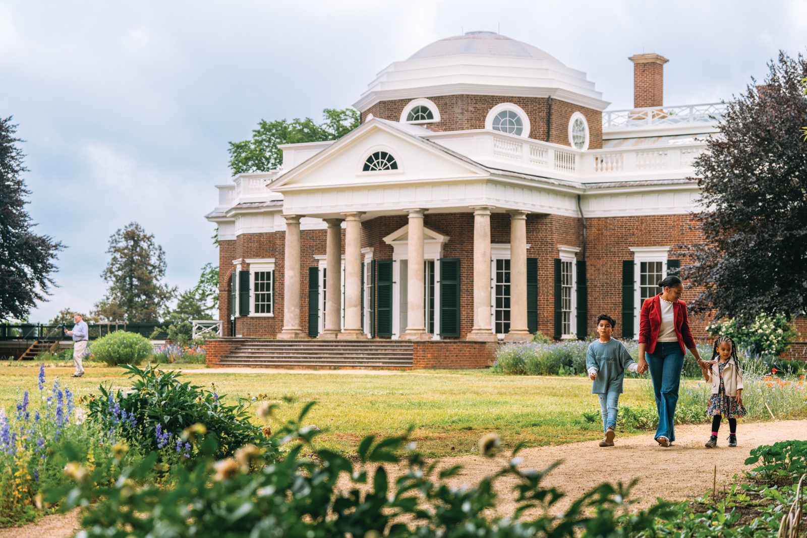 Family walking past garden beds in front of Thomas Jefferson’s domed Monticello in Charlottesville, Virginia