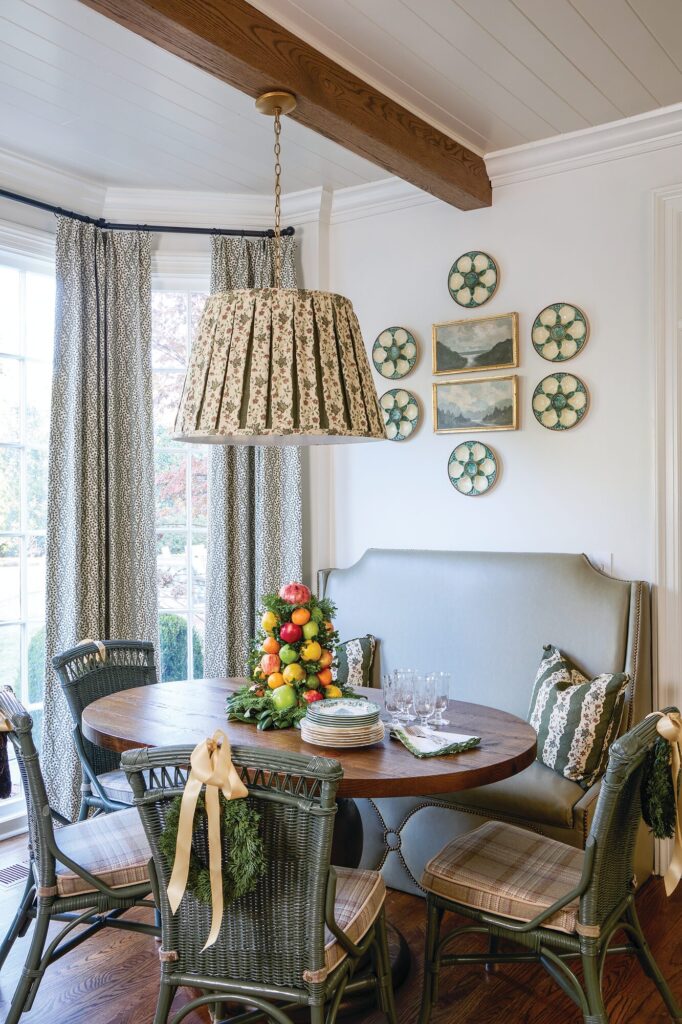 Breakfast room with antique wicker chairs, a custom banquette, and a pleated lampshade-style pendant
