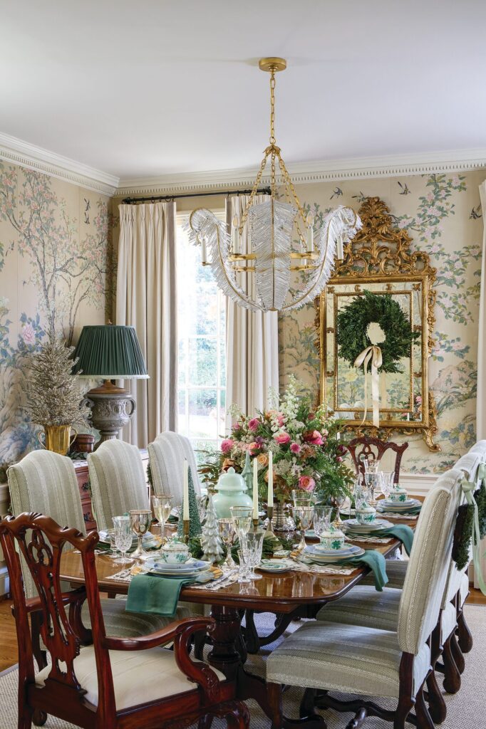 Dining room with original hand-painted floral wallpaper panels, gilt mirror with wreath, and a holiday table setting