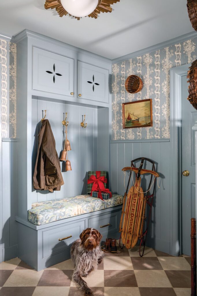 Drop zone with blue beaded board paneling, Scalamandré floral stripe wallcovering, and a vintage sled