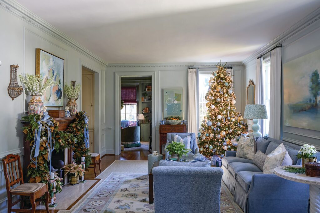 Living room with original wooden mantel, abstract painting by the homeowner, vintage crystal sconces, and blue tweed upholstery