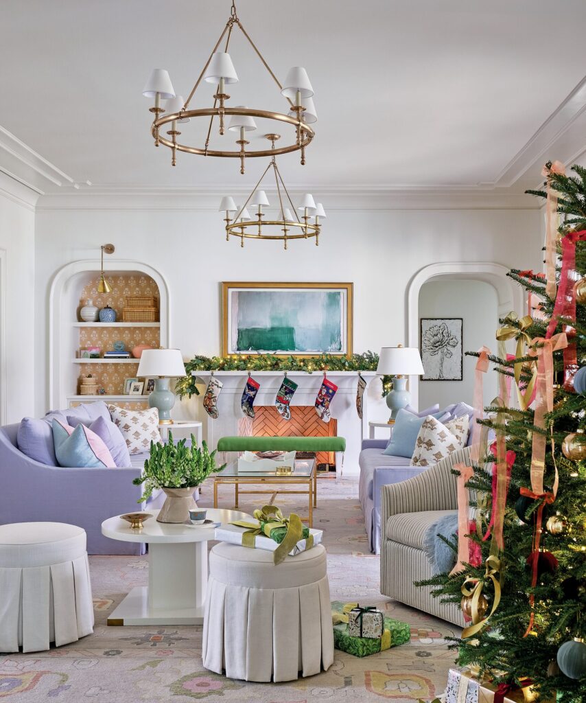 Family room mantel hung with needlepoint stockings beneath abstract art, with lavender and green furnishings