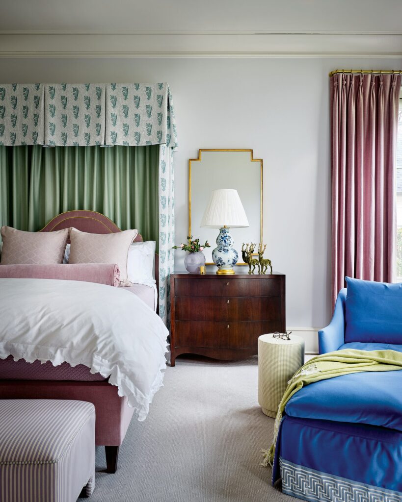 Primary bedroom with a green-trimmed half-tester bed, pink velvet headboard, and a deep blue chaise