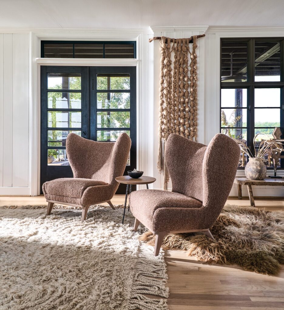 Pair of Gemma high-back chairs in mauve boucle with curved winged sides on a shag rug by black French doors
