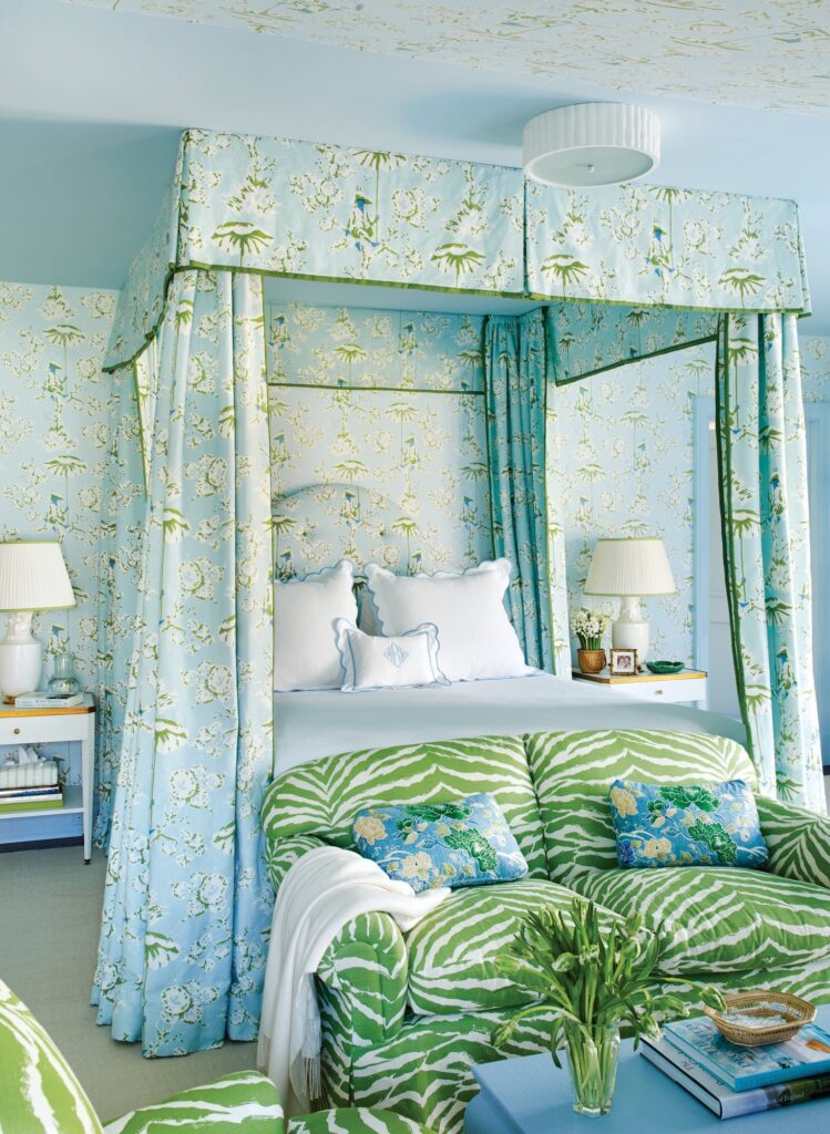 Guest bedroom with a blue-and-green floral canopy bed, matching wallpaper, and a green zebra-print sofa