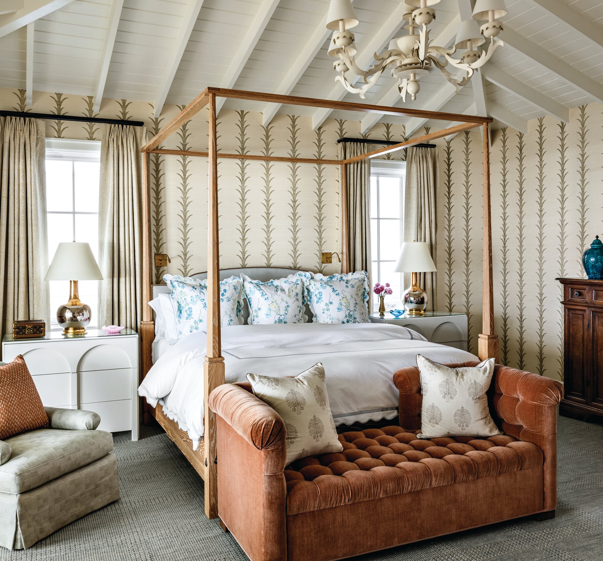 Primary bedroom with a pitched ceiling and exposed rafters, a white oak four-poster bed, vertical-stripe wallpaper, and a rust velvet tufted settee