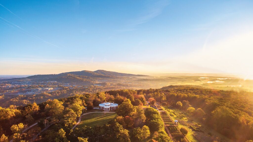 Aerial view of Monticello among autumn trees with the Blue Ridge foothills glowing in golden light