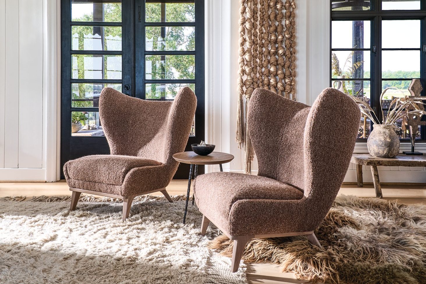 Pair of Gemma high-back wing chairs in mauve boucle on a shag rug in front of black French doors